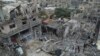 Warga Palestina melihat-lihat di sekitar bangunan yang hancur akibat pengeboman Israel di kamp pengungsi Nuseirat di Jalur Gaza pada Minggu, 29 Oktober 2023. (Foto: AP/Hatem Moussa)
