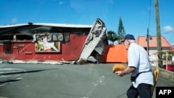 A man walks past a damaged supermarket in Noumea, France's Pacific territory of New Caledonia, on May 24, 2024. 