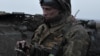 FILE - A Ukrainian soldier uses his mobile phone on front line near Bakhmut, in Ukraine's Donetsk region, partially occupied by Russian forces, March 11, 2023.