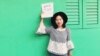 FILE - In this photo released by #FreeXueBing, Chinese journalist Huang Xueqin holds up a #METOO sign for a photo in Singapore in September 2017.