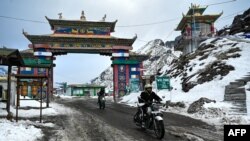 FILE - Pengendara sepeda motor menyeberang ke jalur Himalaya Sela yang sarat salju di Tawang, negara bagian Arunachal Pradesh, India timur laut, 5 April 2023.