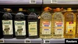 FILE - Olive and sunflower oil bottles are displayed for sale, protected by a padlock and a chain to prevent theft, in a Tu Super Suma supermarket in Malaga, Spain, Oct. 23, 2023.