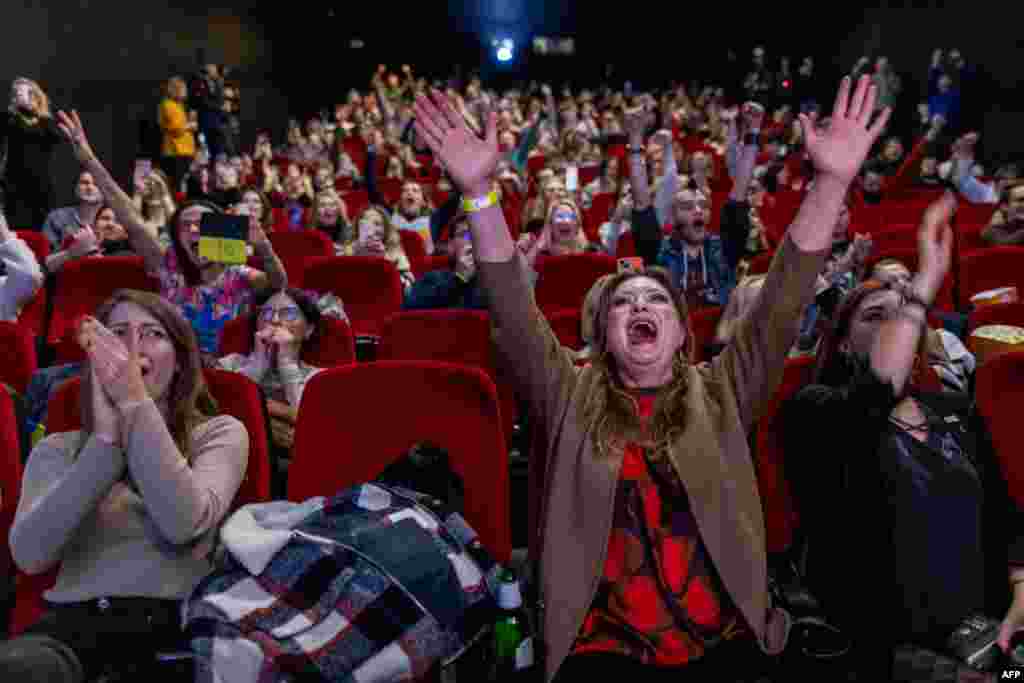 People react as they watch a parliament session on a confidence vote of outgoing Polish prime minister Mateusz Morawiecki, in a cinema in Warsaw.&nbsp;