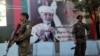 Afghan security forces stand guard in front of an election poster for presidential candidate Ashraf Ghani in Kabul, Afghanistan, Sept. 23, 2019. 