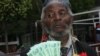 Holding bills of new Zimbabwean money, a man welcomes the introduction of bond notes saying the move will ease cash shortages in the country, in Harare, Zimbabwe, Nov. 28, 2016. (S. Mhofu/VOA)