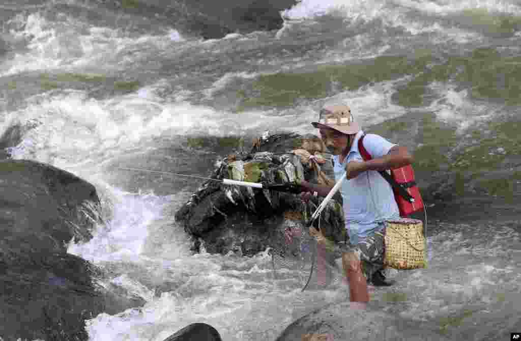A man uses a net to catch fish in a stream in Bogor, West Java, Indonesia.