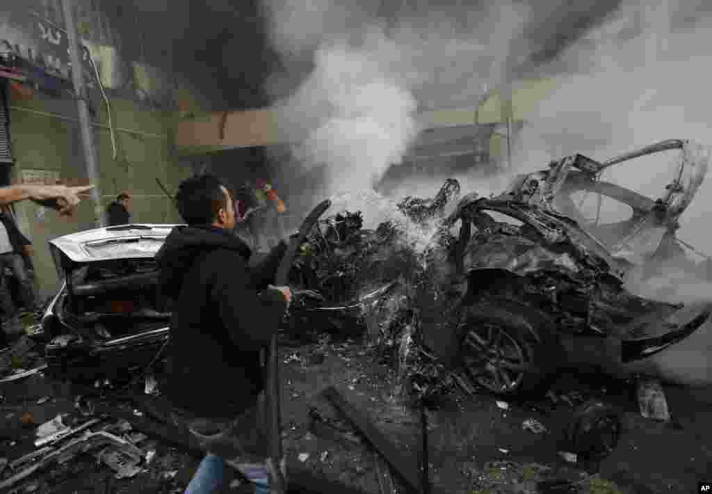 A man extinguishes burned cars at the site of a car bomb explosion in a southern suburb of Beirut, Jan. 2, 2014.