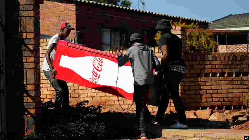 Des manifestants transportent un réfrigérateur Coca Cola qu&#39;ils ont pillé dans un magasin, lors des manifestations à Atteridgeville, en Afrique du Sud, le 21 juin 2016.
