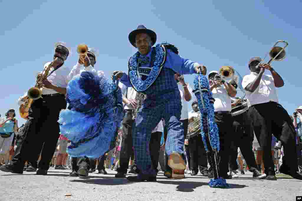 Members of the Keep N It Real Social Aid & Pleasure Club march with the New Wave Brass band at the New Orleans Jazz and Heritage Festival in New Orleans, Louisiana.