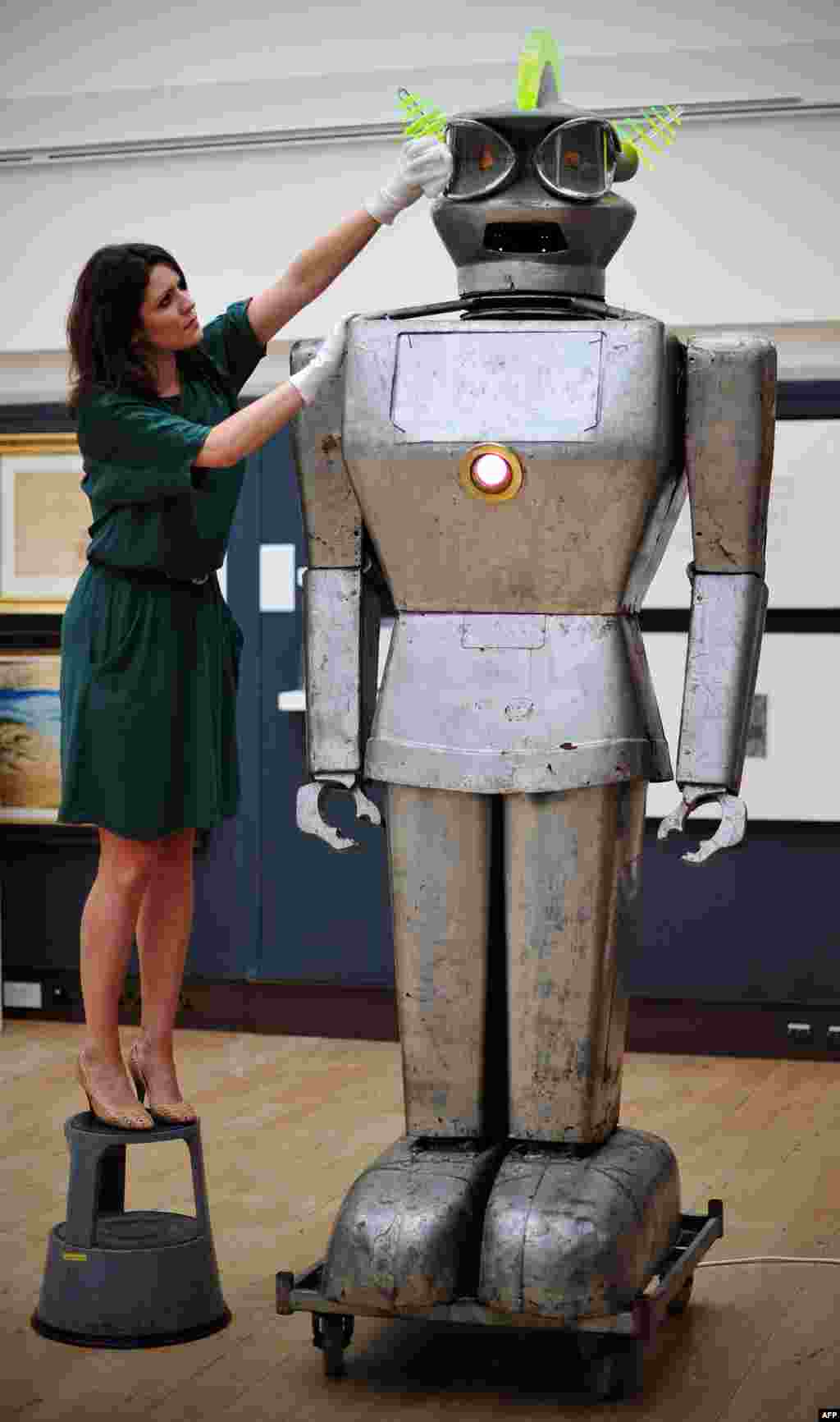 Seorang anggota staf rumah lelang Christie&#39;s di pusat kota London, Inggris berpose dengan sebuah robot yang disebut &#39;Cygan&#39;. Cygan merupakan salah satu robot tercanggih pada masanya, yang memiliki kemampuan untuk menerima perintah yang diucapkan dan merespon cahaya. (AFP PHOTO / CARL COURT)