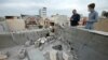 FILE – People stand next to a damaged roof after a rocket attack on U.S.-led forces near Irbil International Airport in Irbil, Iraq, Feb. 16, 2021. U.S. forces in Iraq and Syria have come under attack at least five times in the past two days, according to U.S. defense officials,