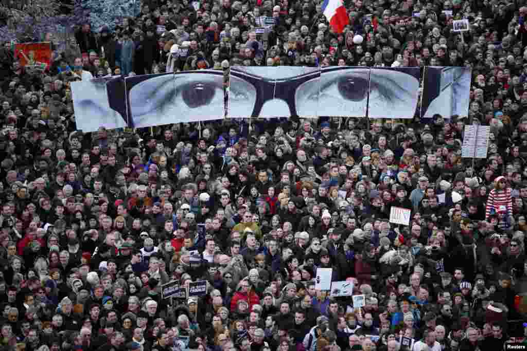 People hold panels to create the eyes of late Charlie Hebdo editor Stephane Charbonnier, known as "Charb", as hundreds of thousands of French citizens take part in a solidarity march (Marche Republicaine) in the streets of Paris, Jan. 11, 2015. French citizens were joined by dozens of foreign leaders in a march in an unprecedented tribute to this week's victims following the shootings by gunmen at the offices of the satirical weekly newspaper Charlie Hebdo, the killing of a police woman in Montrouge, and the hostage taking at a kosher supermarket at the Porte de Vincennes.