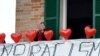 Une femme sur son balcon où elle a mis des ballons rouges portant le nom des victimes et une banderole disant "non au racisme" lors d'une manifestation antiraciste dans la ville de Macerata, en Italie, le 10 février 2018.