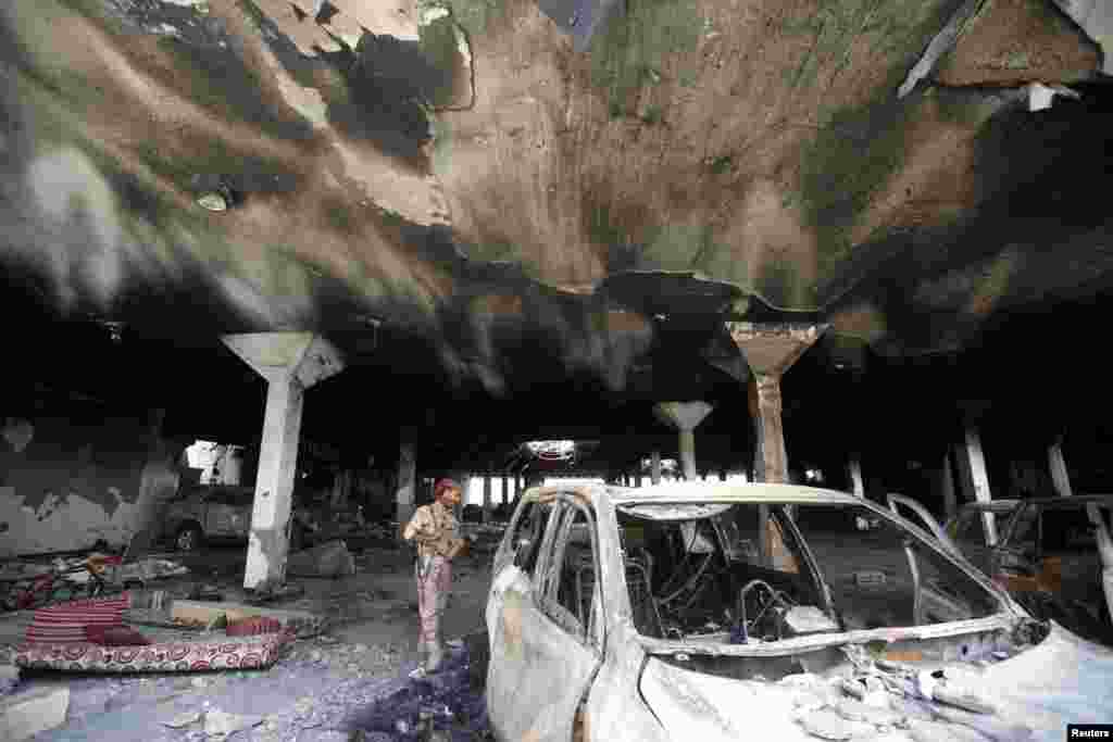 Seorang petugas keamanan mengamati sebuah mobil yang rusak saat kunjungan para aktivis HAM di Sana&#39;a, Yaman, di lokasi di mana pasukan koalisi pimpinan Saudi membom warga yang sedang menghadiri acara pemakaman.
