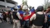 FILE - Anti-government protesters holding a Haitian flag confront security forces during a march in Port-au-Prince, Haiti, Oct. 20, 2019. 