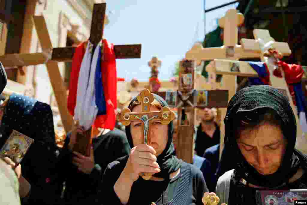 Orthodox Christian worshippers hold crosses before a procession along the Via Dolorosa on Good Friday during Holy Week in Jerusalem&#39;s Old City.