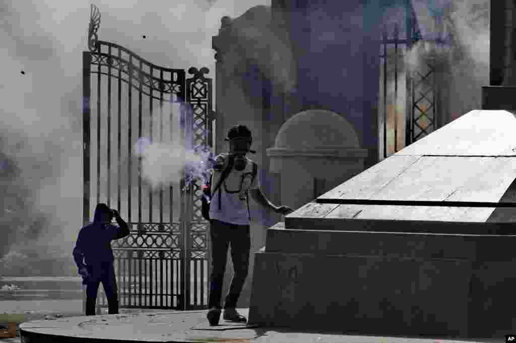 Seorang demonstran menembakkan pijar dalam bentrokan dengan pasukan keamanan di luar Cairo University di Giza (26/3).&nbsp;(AP/Ahmed Abdel Fattah, El Shorouk)&nbsp;
