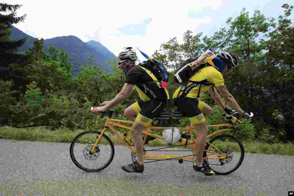 Ake Johansson dari Swedia (kiri), dan temannya mendaki lintasan L&#39;Epine di atas sepeda tandem buatan sendiri dalam tahapan ke-19 Tour de France.