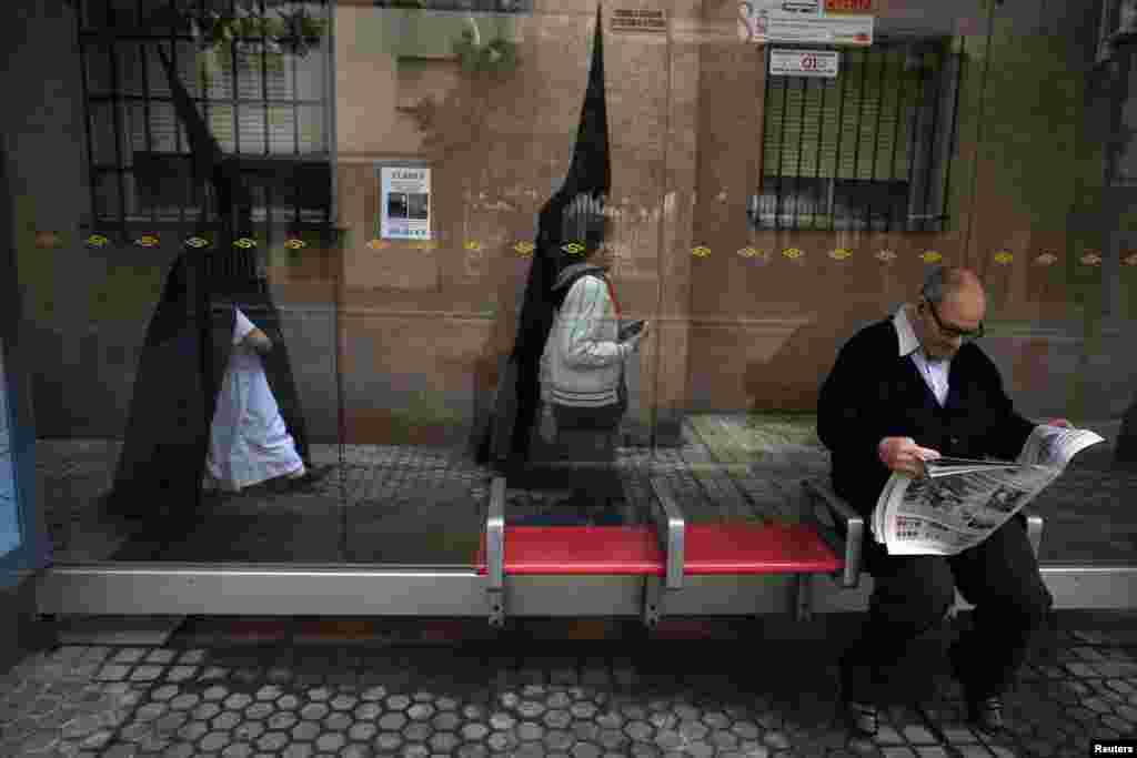 Dua orang berangkat ke gereja mereka sebelum mengambil bagian dalam prosesi "Santa Genoveva" selama Pekan Suci di kota Sevilla, Spanyol selatan. Ratusan prosesi Paskah berlangsung di Sevilla selama Pekan Suci, menarik ribuan pengunjung.