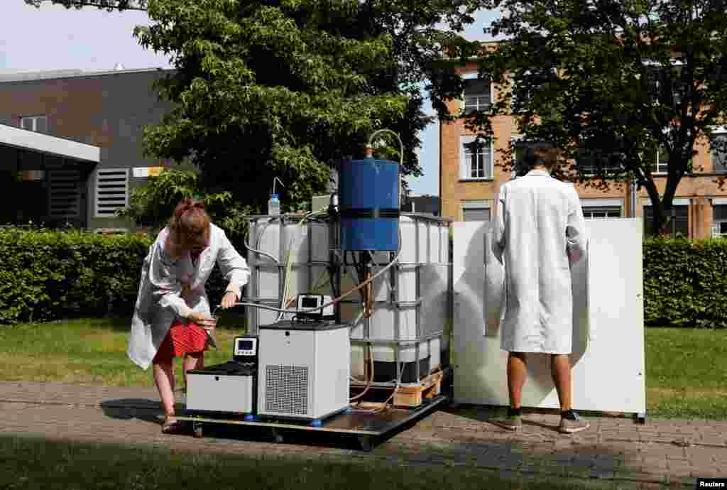 Belgian scientists Marjolein Vanoppen and Sebastiaan Derese (R) demonstrate the use of a machine that turns urine into drinkable water and fertilizer using solar energy, at the University of Ghent, Belgium.