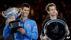 Petenis Serbia Novak Djokovic, kiri, memegang piala bersama petenis Skotlandia Andy Murray setelah memenangkan kejuaraan tenis Australia Terbuka di Melbourne, Australia, 1 Februari 2015.