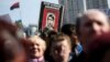 People hold a sign depicting Russian President Vladimir Putin as Adolf Hitler as they attend a unity rally at Independence Square, in Kyiv, Ukraine, March 23, 2014.
