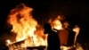 A masked anti-government protester stands by a burning street barricade in Santiago, Chile, Oct. 28, 2019. 