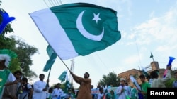 FILE - A man from the Pakistan's Hindu community waves a national flag during a rally expressing solidarity with the people of Kashmir, in Peshawar, Pakistan, Aug. 14, 2019. 