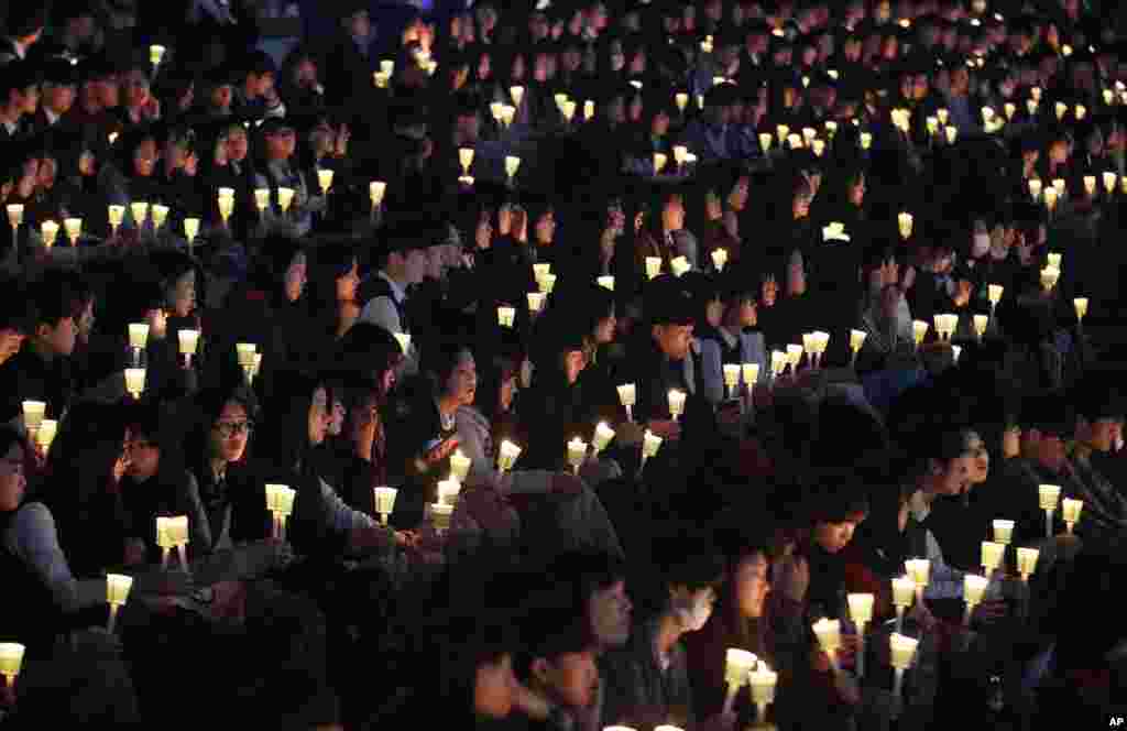 High school students hold candles to pay their respects to the victims of sunken ferry Sewol during a ceremony on the eve of the second anniversary of the sinking in Ansan, South Korea.