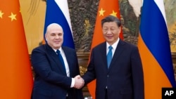 FILE - In this photo released by Xinhua News Agency, visiting Russian Prime Minister Mikhail Mishustin, left, shakes hands with Chinese President Xi Jinping before their talks in Beijing on Dec. 20, 2023.