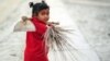 FILE - Young Indian child Laxmi carries a broom and hoe as she walks with her mother after working at the site of the annual traditional fair Magh Mela at Sangam, the confluence of the rivers Ganges and Yamuna, and the mythical Saraswati in Allahabad on January 2, 2015.