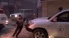 An image grab from a February 8, 2014 Youtube video shows a man running to take cover as U.N. vehicles, one of the World Food Program (R), stopped after a shelling targeted their aid convoy in the besieged districts of Syrian city of Homs. 