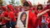 A pro-government Red Shirt member dances with a portrait of Thai Prime Minister Yingluck Shinawatra during a rally in Bangkok, April 5, 2014. 