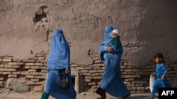 FILE - Afghan women walk with their children through the old quarters of Herat, Sept. 20, 2016. 