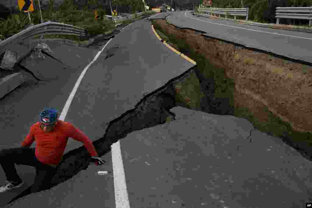 A man jokes around after taking some pictures of a section of highway that collapsed due to a 7.8-magnitude earthquake, in Chacras, Ecuador, April 19, 2016.