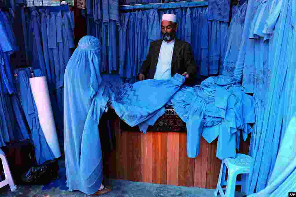 Seorang perempuan Afghanistan memilih-milih 'burqa' pada sebuah bazaar di kota Herat.