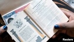 Une femme montre les passeports de sa famille avec un visa américain à Accra, au Ghana, le 1er février 2019. Le Ghana n'est pas inclus dans le programme de garantie monétaire.