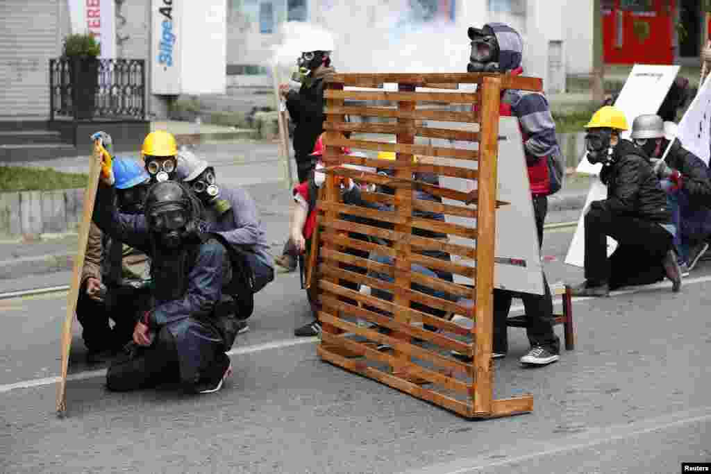 Para pengunjuk rasa melindungi diri mereka dari polisi selama demo dalm rangka memperingati Hari Buruh Internasional di Istanbul, Turki.