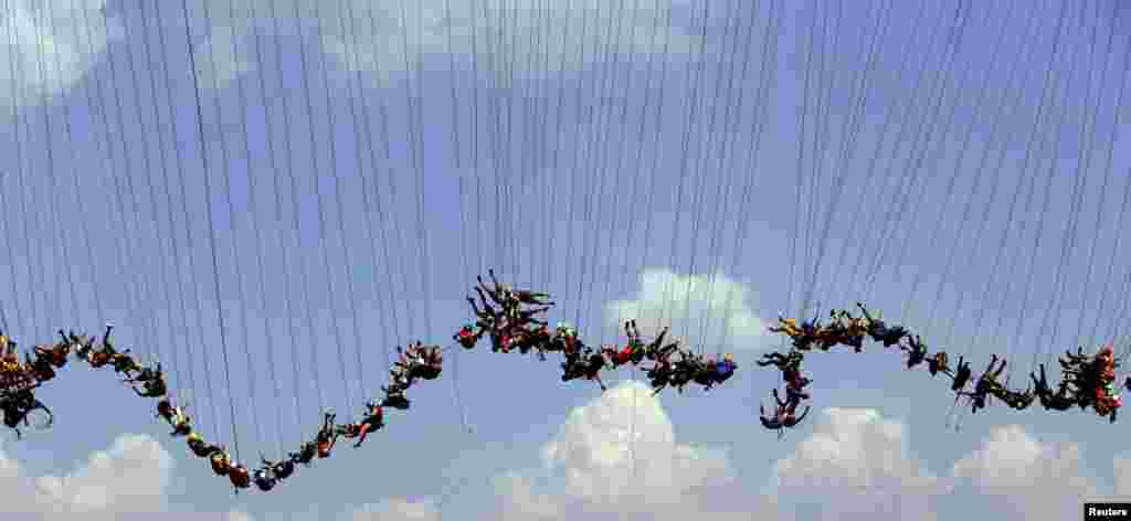 People jump off a bridge, which has a height of 30 meters, in Hortolandia, Brazil, April 10, 2016. According to organizers, 149 people were attempting set a new world record for "rope jumping", in which people, tied to a safety cord, jump off a bridge.