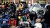 Refugees and migrants sit next to their belongings before boarding a bus heading to other parts of the country where they will be accommodated, at the port of Piraeus, near Athens, Greece, March 31, 2016.