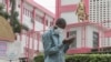 FILE - A man wears a mask while walking outside the entrance to the Yaounde General Hospital in Yaounde, March 6, 2020.