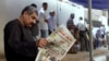 A man reads a local newspaper with the headline in Arabic reading, "Egypt surprises the world," outside a polling station in Cairo, May 27, 2014.