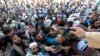Afghan men wait to collect tokens needed to apply for the Pakistan visa, in Jalalabad, Afghanistan, Oct. 21, 2020. 