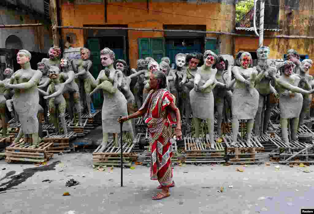 Seorang perempuan melewati patung-patung yang belum selesai dari karakter mitologi Hindu &#39;Dakinis&#39; dan &#39;Yoginis,&#39; menjelang perayaan festival keagamaan &#39;Kali Puja&#39; di Kolkata, India.