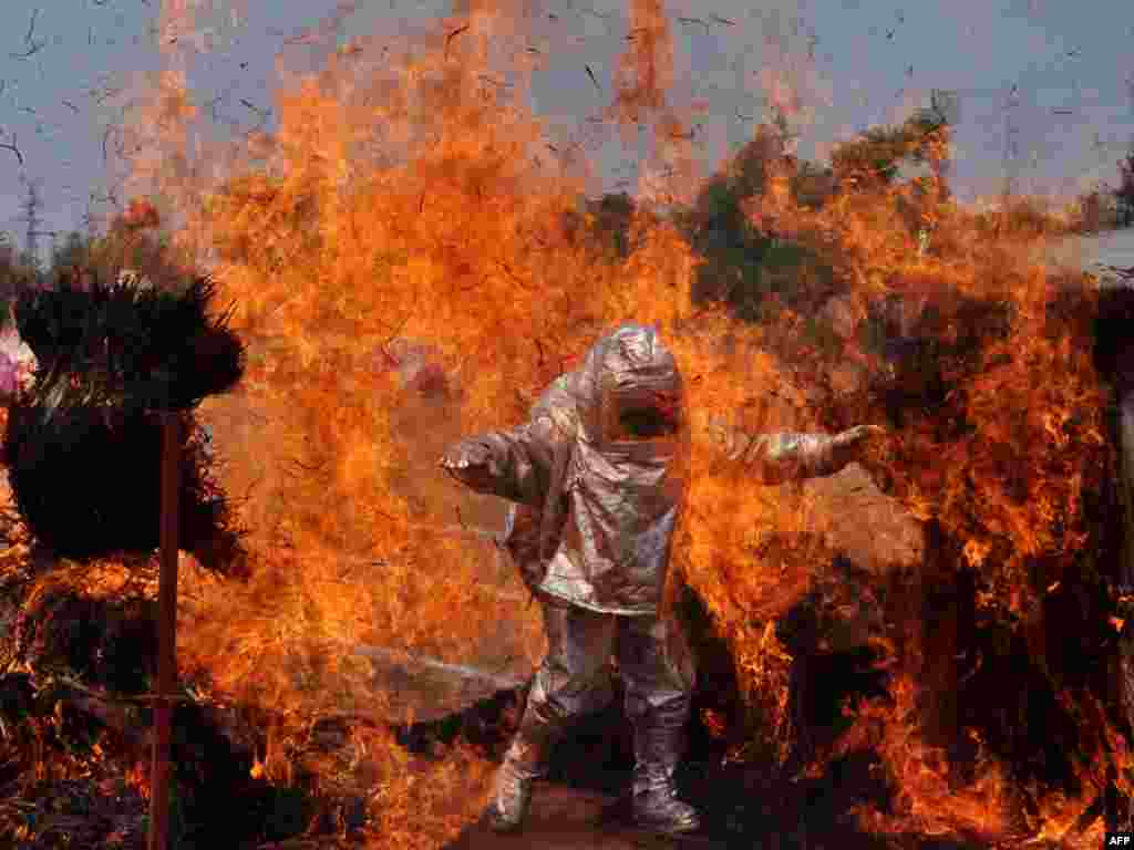 An Indian firefighter wearing a fire proximity suit walks through a wall of flames during a demonstration of firefighting skills for Fire Safety Week in Bhubaneswar. Fire Safety Week runs April 14-20 across India.