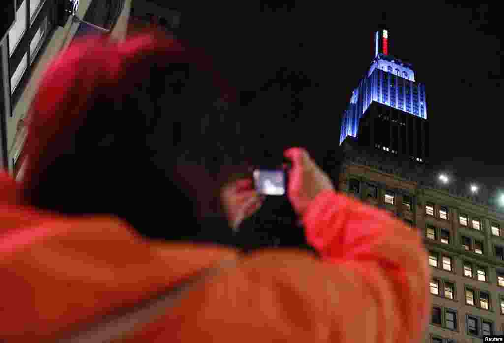 Seorang perempuan mengambil foto gedung Empire State Building yang bermandikan cahaya biru, warna Partai Demokrat, setelah Barack Obama diproyeksikan menang pemilu. (Reuters/Carlo Allegri)