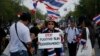 A protester holds a placard denouncing the government outside the government house in attempts to "shutdown" Bangkok, Thailand, Feb. 17, 2014.