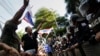 Anti-government protesters gesture towards riot police outside the headquarters of the ruling Pheu Thai Party of Prime Minister Yingluck Shinawatra in Bangkok, Nov. 29, 2013. 