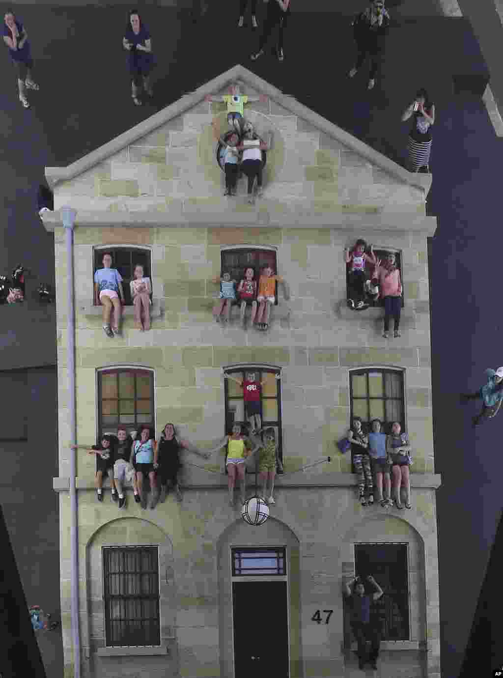 People pretend to hang off ledges and windowsills on an unusual architectural display, called &quot;Merchants Store,&quot; during the Sydney Festival in Sydney, Australia.