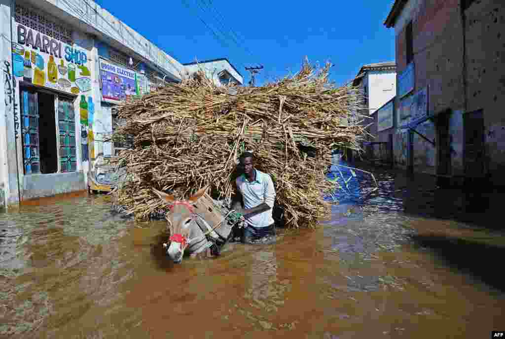 A man walks his donkey and its load through the flooded streets of Beledweyne, north of Mogadishu, Somalia.